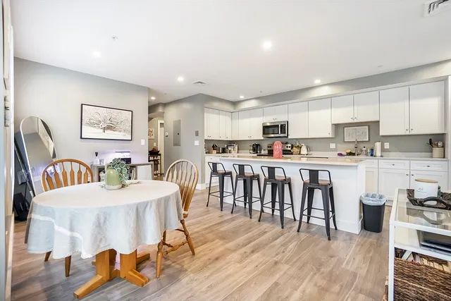 a kitchen with stainless steel appliances granite countertop a refrigerator a stove a sink a dining table and chairs with wooden floor