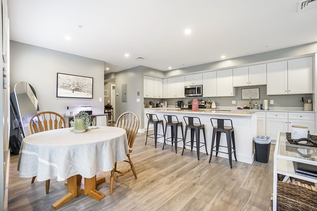 245 Bussey Street, Unit 205 Dedham, MA 02026 - Photo 2 of 17 a kitchen with stainless steel appliances granite countertop a refrigerator a stove a sink a dining table and chairs with wooden floor