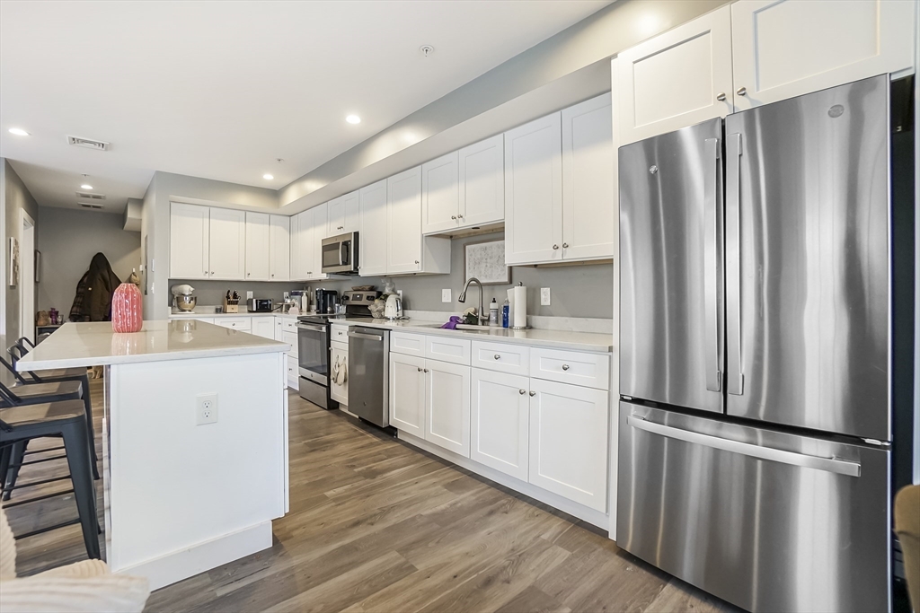 245 Bussey Street, Unit 205 Dedham, MA 02026 - Photo 5 of 17 a kitchen with stainless steel appliances a refrigerator sink and cabinets