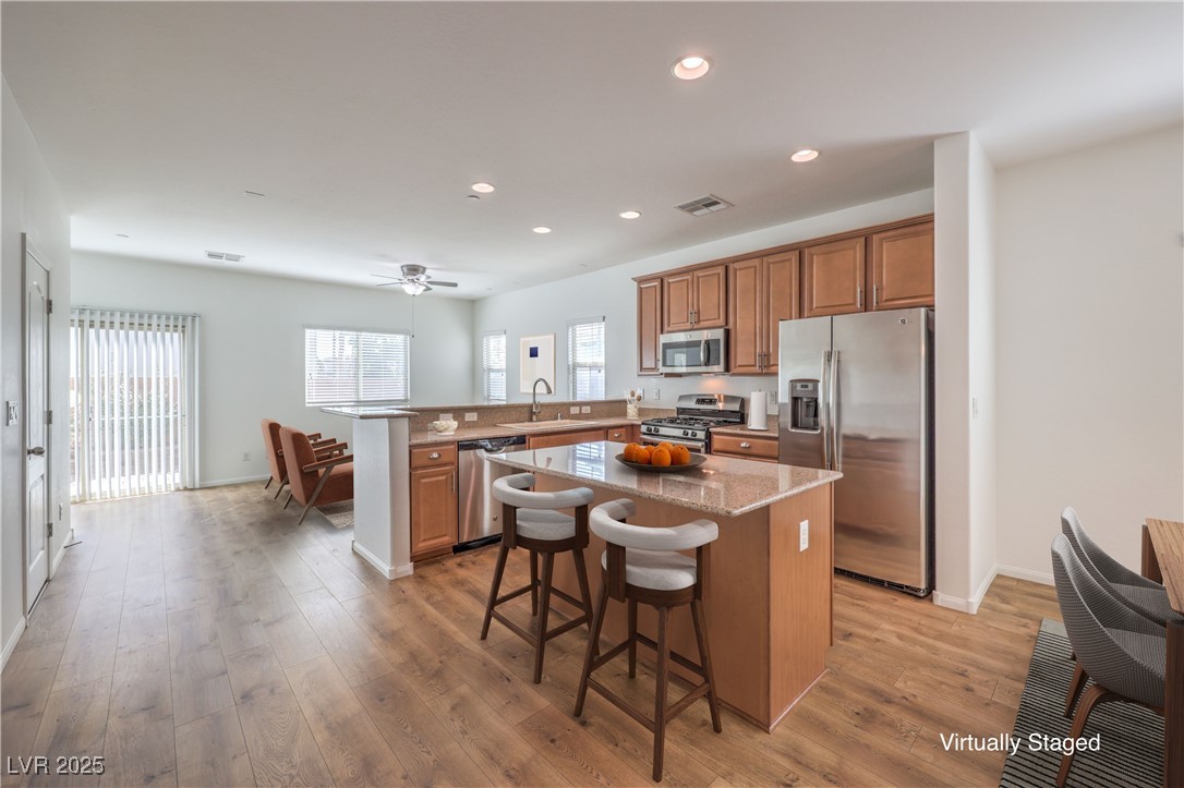 Virtually Staged; Kitchen featuring a kitchen bar, stainless steel appliances, & island recessed lighting