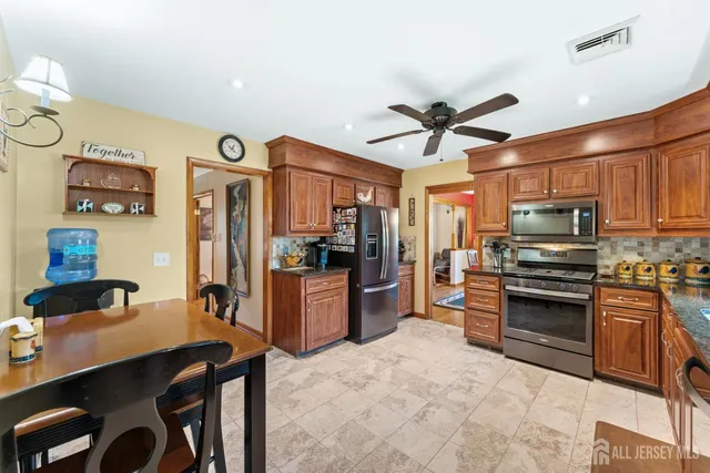 a kitchen with stainless steel appliances granite countertop a stove top oven a refrigerator and a sink