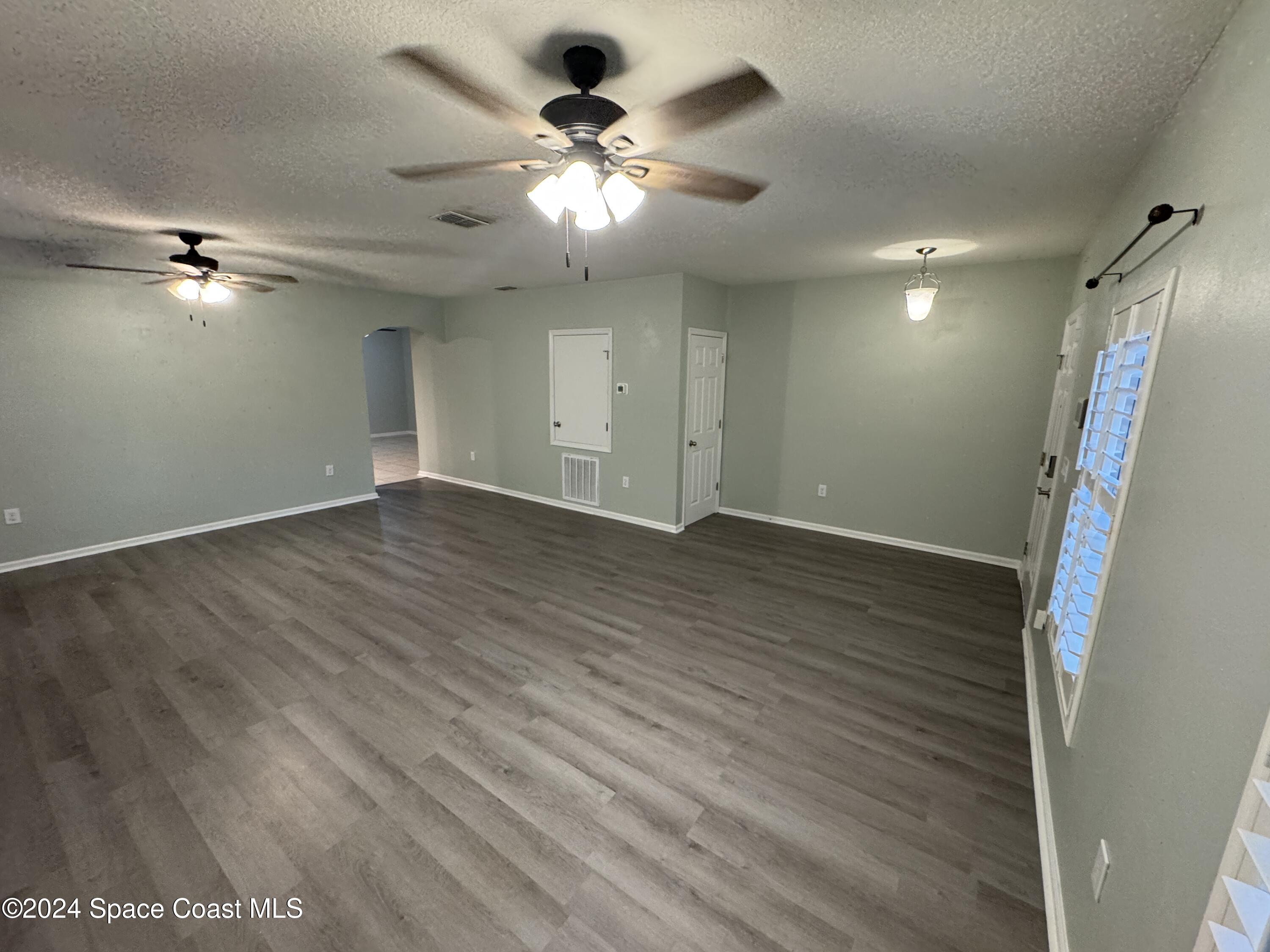 5281 Talbot Boulevard Cocoa, FL 32926 - Photo 3 of 31 an empty room with wooden floor fan and window