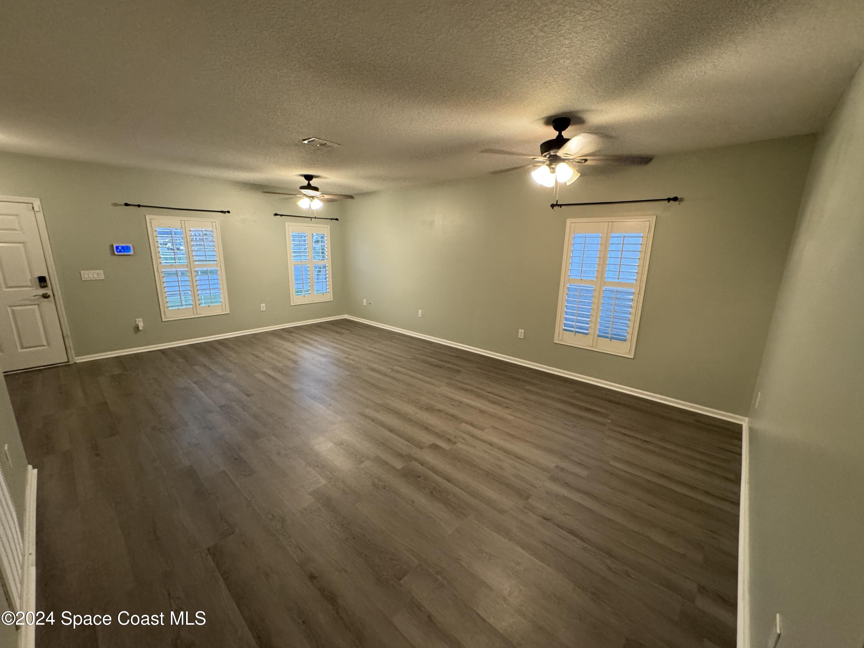 5281 Talbot Boulevard Cocoa, FL 32926 - Photo 6 of 31 an empty room with wooden floor chandelier fan and windows