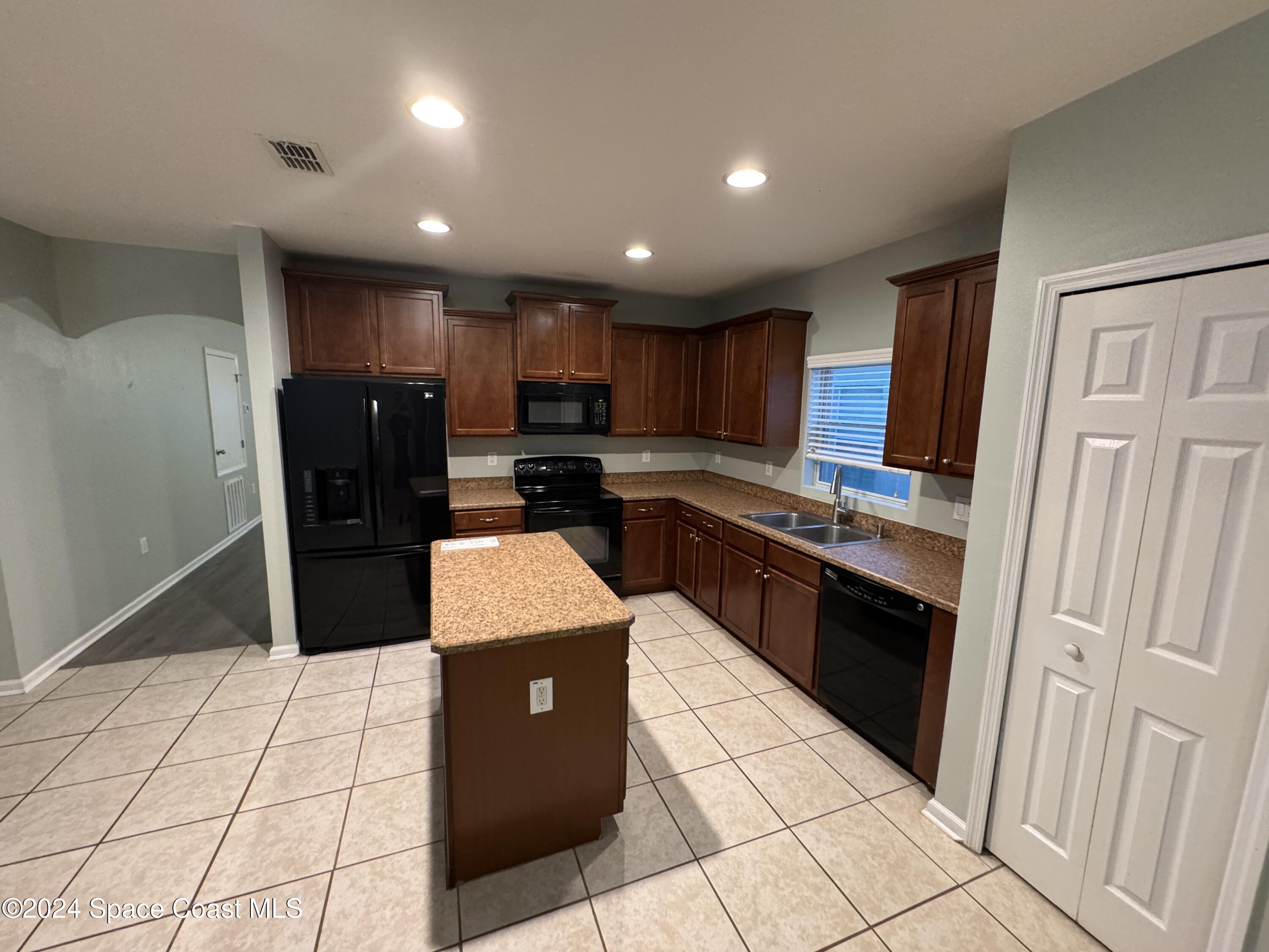 5281 Talbot Boulevard Cocoa, FL 32926 - Photo 10 of 31 a kitchen with stainless steel appliances granite countertop a refrigerator stove and a sink with wooden cabinets