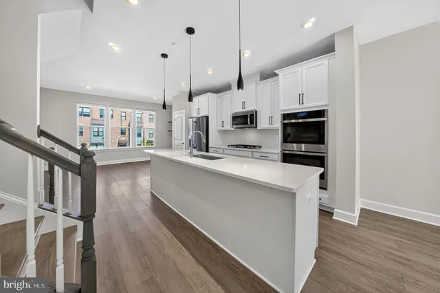 a kitchen with stainless steel appliances kitchen island granite countertop a stove a refrigerator a sink and a wooden floor