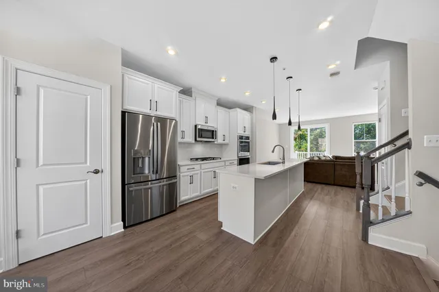 a large kitchen with stainless steel appliances a refrigerator a stove a sink dishwasher and a oven with wooden floor