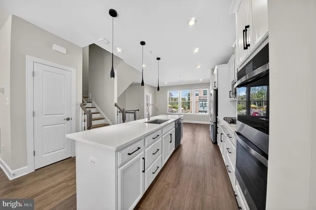 a kitchen with counter top space stainless steel appliances and wooden floor