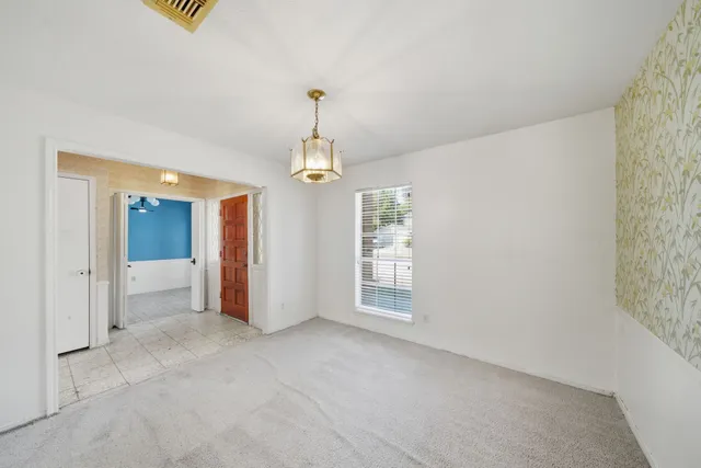a view of an empty room with chandelier and window
