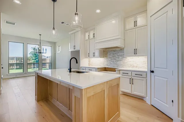 a kitchen with white cabinets and sink