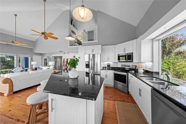 a kitchen with stainless steel appliances granite countertop a stove top oven a sink dishwasher a dining table and chairs with wooden floor