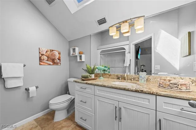 a bathroom with a granite countertop toilet sink and mirror