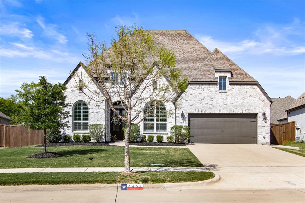 French country home featuring fence, a front lawn, brick siding, an attached garage, and concrete driveway