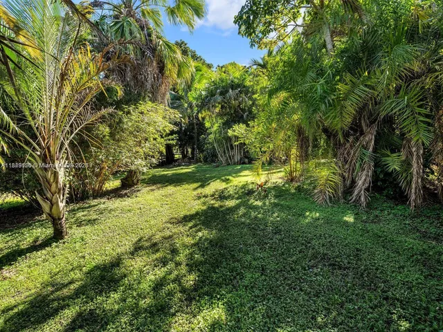 an aerial view of residential houses with outdoor space and trees