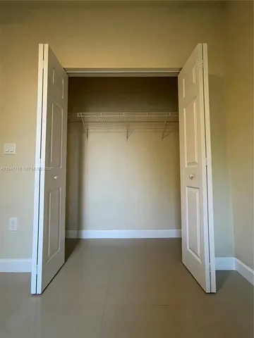 a view of a hallway with closet and a bathroom
