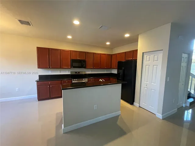 a large kitchen with stainless steel appliances a large counter top a fireplace and a chandelier