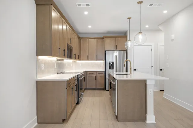 a kitchen with kitchen island granite countertop a sink a stove and refrigerator