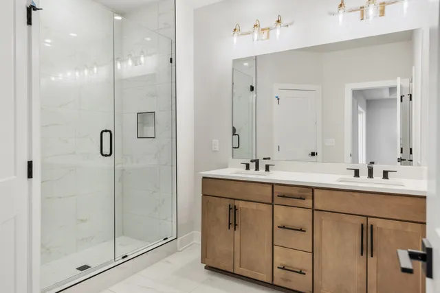 a bathroom with a double vanity sink mirror and shower