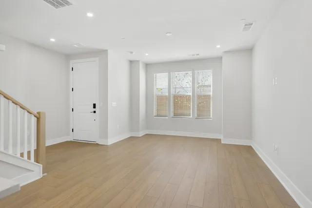 a view of an empty room with wooden floor and window
