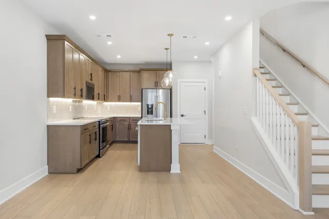 a large white kitchen with a large counter top a sink stainless steel appliances and cabinets