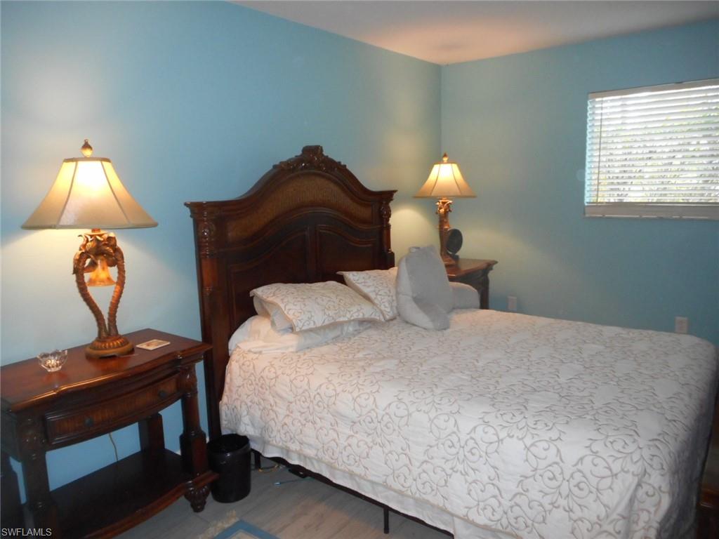 1007 Pine Isle Lane, Unit 1007 Naples, FL 34112 - Photo 12 of 22 a bedroom with a bed and a lamp on desk