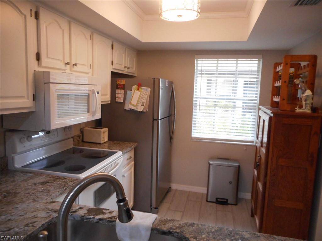 1007 Pine Isle Lane, Unit 1007 Naples, FL 34112 - Photo 6 of 22 a kitchen with granite countertop white cabinets and black appliances