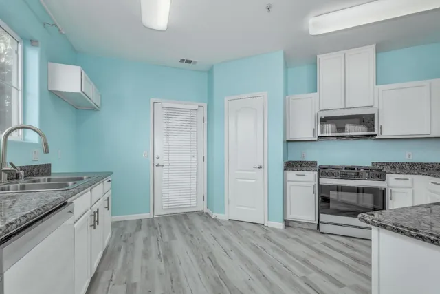 a kitchen with stainless steel appliances granite countertop a sink stove and cabinets