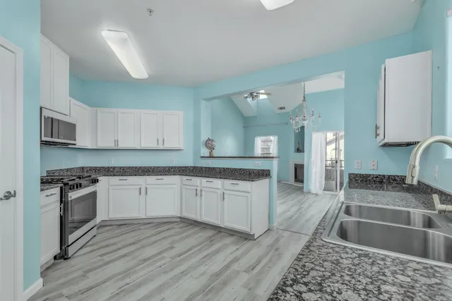 a large kitchen with granite countertop a stove top oven a sink dishwasher a dining table and chairs with wooden floor