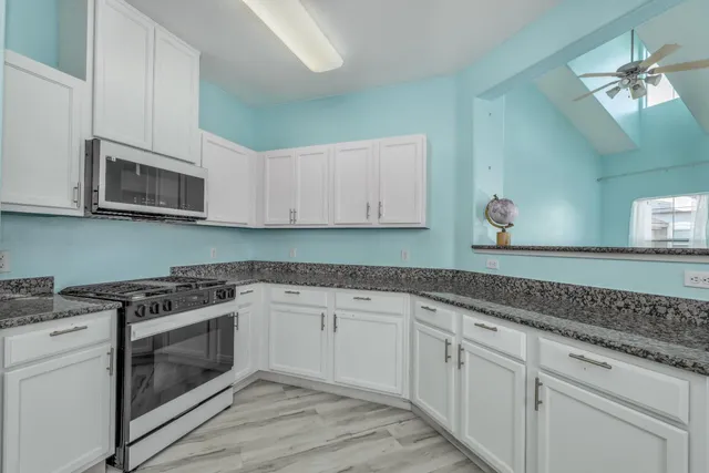 a kitchen with granite countertop white cabinets stainless steel appliances and a sink