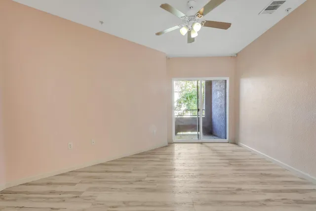 a view of an empty room with window and wooden floor