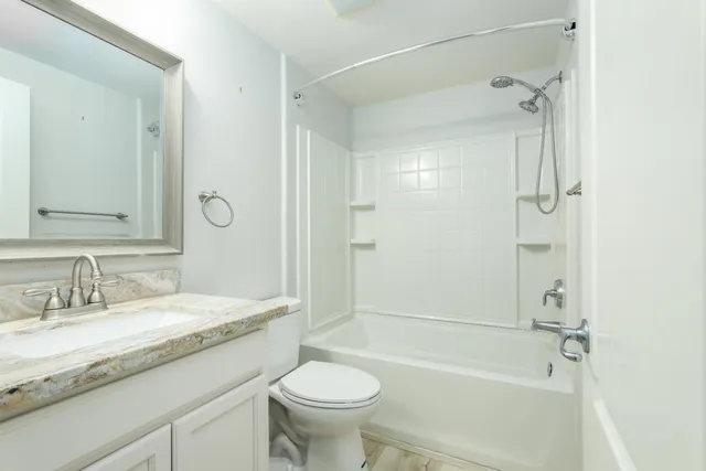 a bathroom with a granite countertop sink toilet mirror and shower