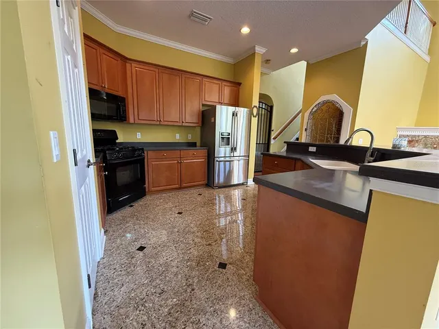 a kitchen with granite countertop a refrigerator and a stove top oven