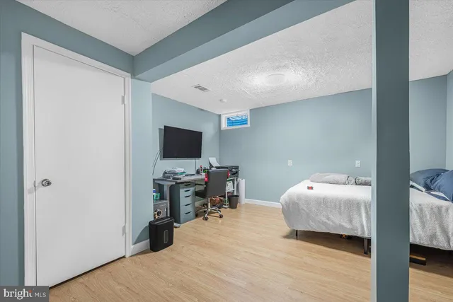 a view of a hallway with wooden floor and a bathroom
