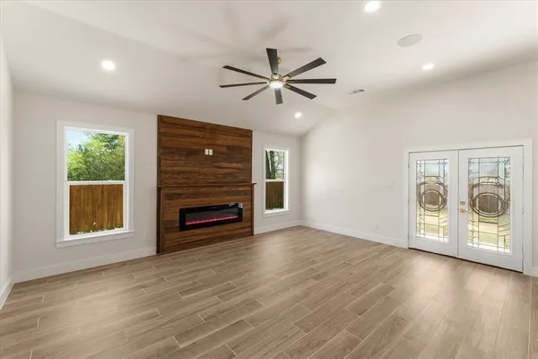 an empty room with windows fireplace and a ceiling fan