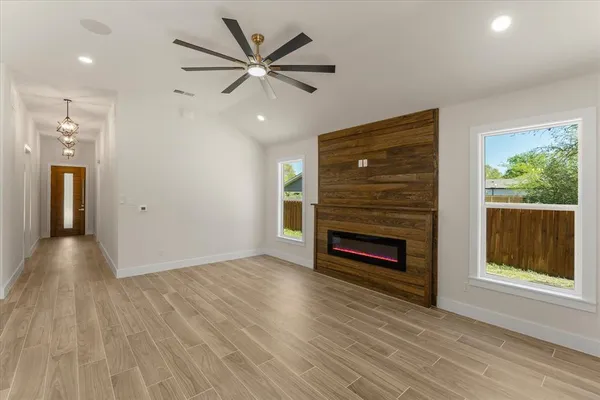 a view of an empty room with wooden floor fireplace and a window