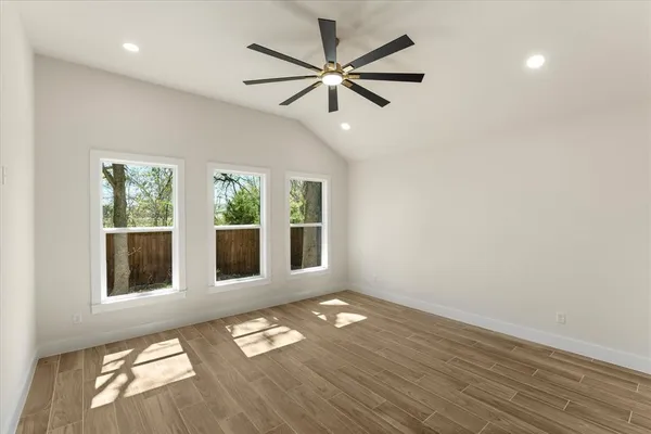 an empty room with wooden floor fan and windows