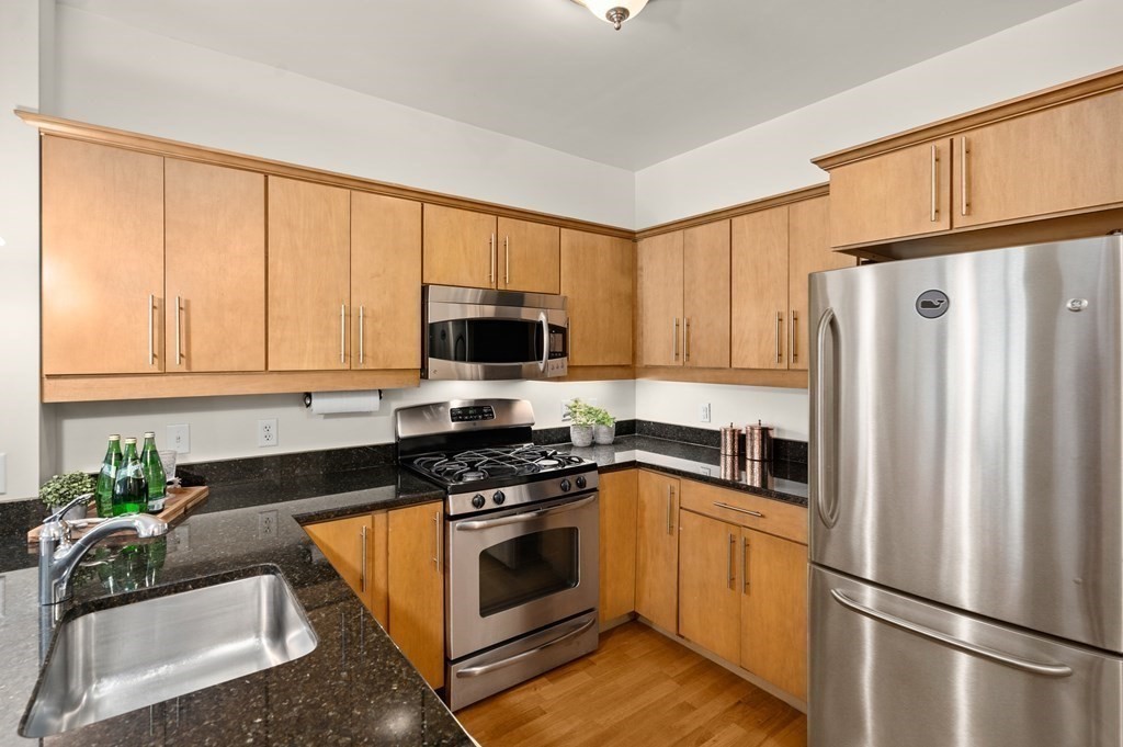 35 Commonwealth Avenue, Unit 103 Newton, MA 02467 - Photo 7 of 23 a kitchen with granite countertop a refrigerator stove and microwave