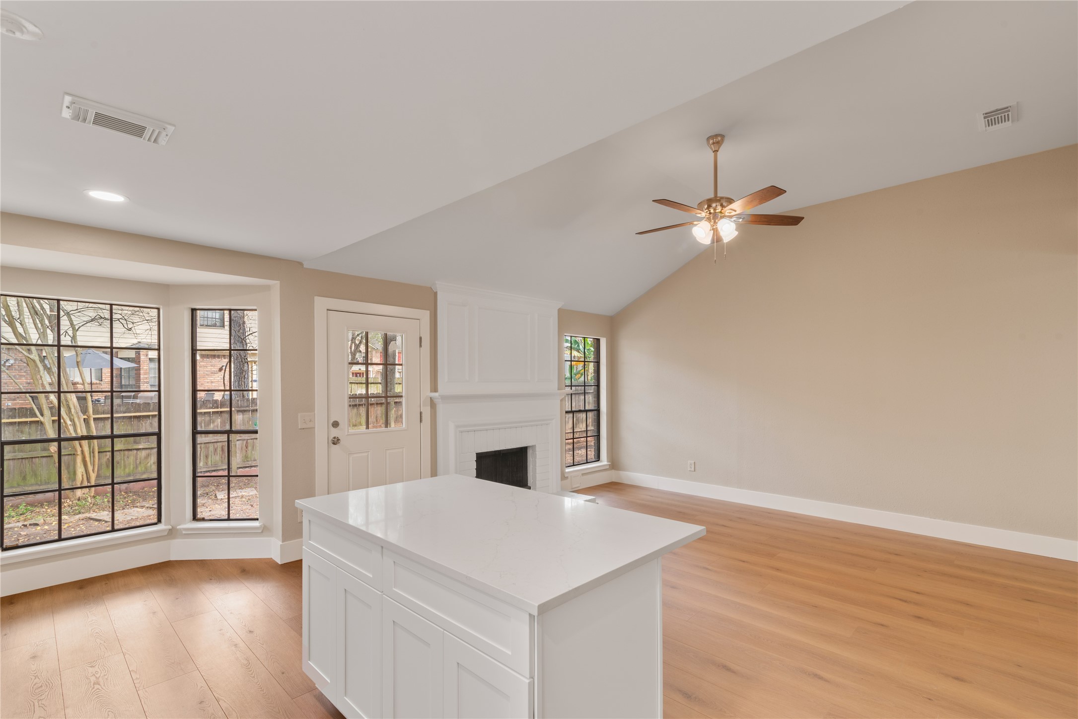 10 White Fawn Drive Spring, TX 77381 - Photo 10 of 25 This bright, open living space features a modern kitchen island, large windows with garden views, and a cozy fireplace. The room is enhanced by high ceilings and a ceiling fan, creating an inviting atmosphere.