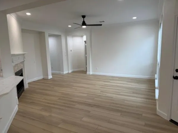 a view of an empty room with wooden floor and a fireplace