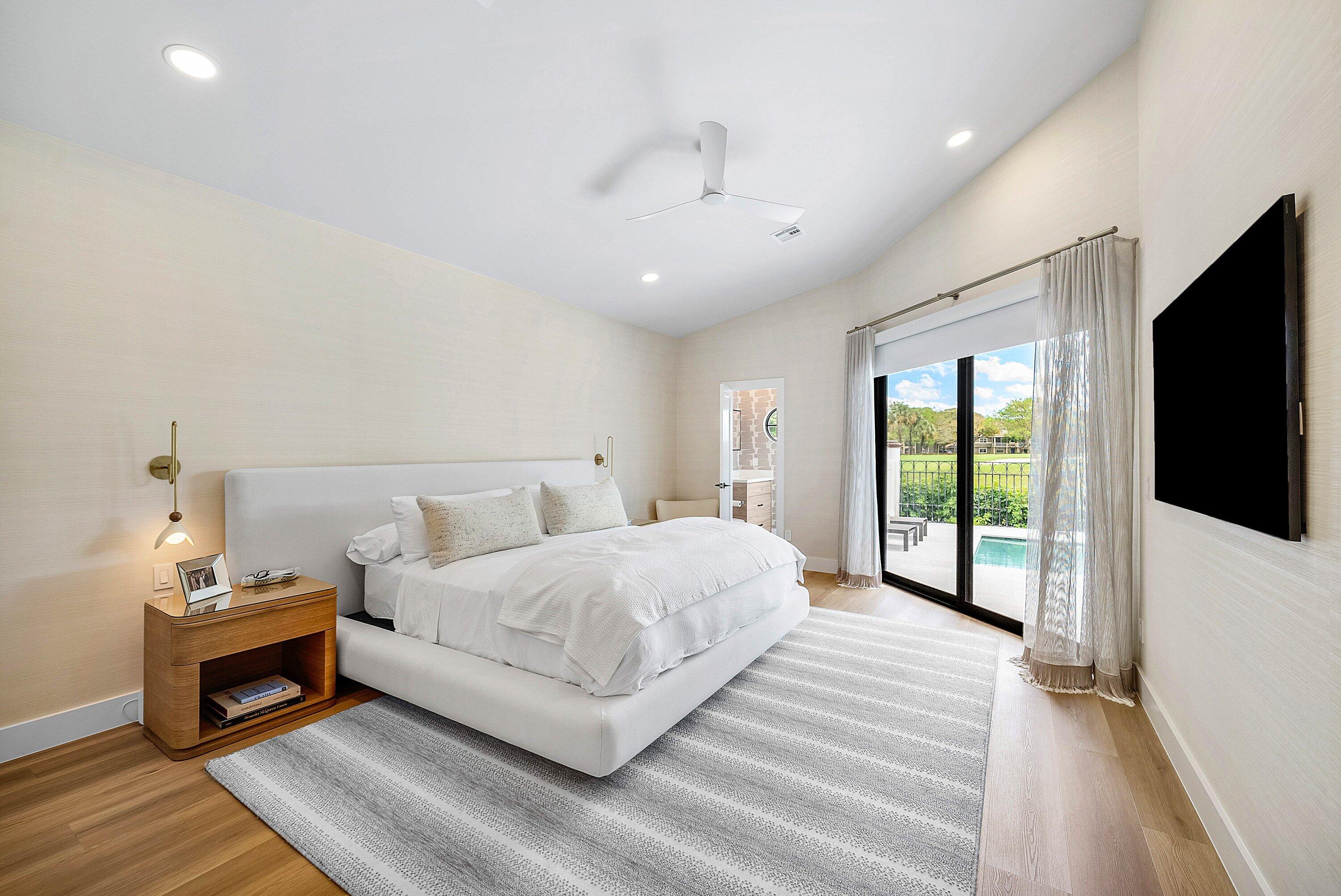 5798 Northwest 21st Avenue Boca Raton, FL 33496 - Photo 12 of 52 a spacious bedroom with a bed a tv and wooden floor