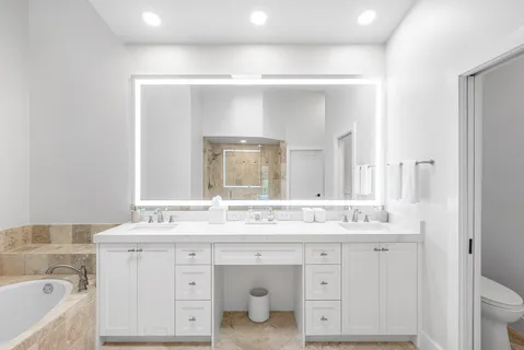 a bathroom with a double vanity sink mirror and bathtub