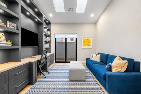a living room with stainless steel appliances furniture and a flat screen tv