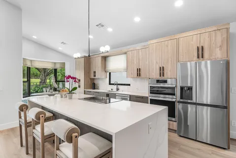 a kitchen with stainless steel appliances a table chairs refrigerator and microwave
