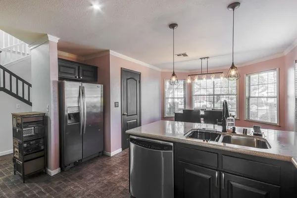 a kitchen with stainless steel appliances granite countertop a refrigerator a sink a stove and a counter top space