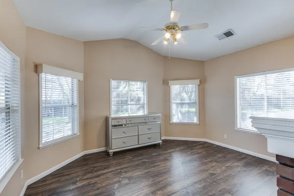 a view of an empty room with a window and wooden floor