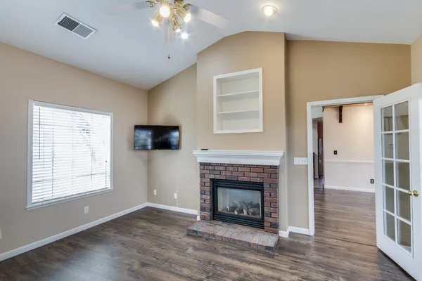 a view of an empty room with wooden floor and a window