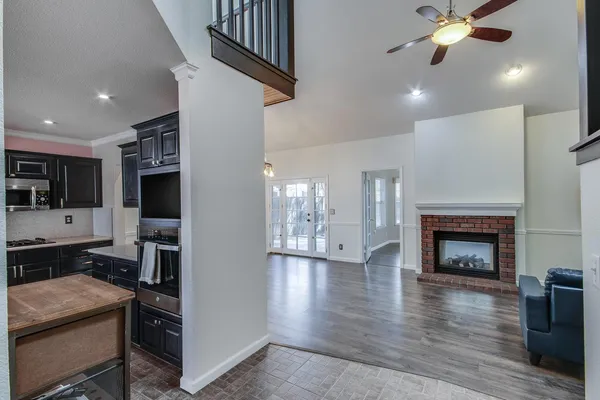 a view of a livingroom with a fireplace wooden floor and a kitchen