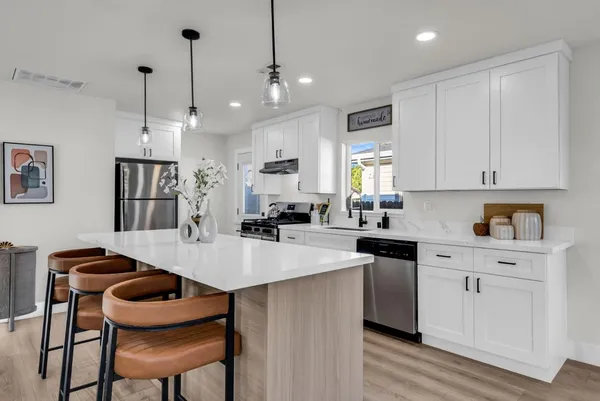 a kitchen with stainless steel appliances granite countertop a table chairs refrigerator and wooden cabinets