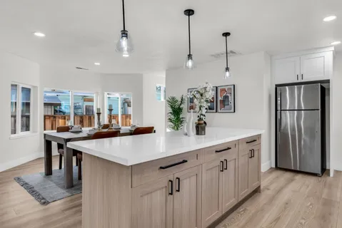 a kitchen with granite countertop kitchen island stainless steel appliances a stove a sink a refrigerator and chairs