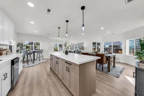 a dining hall with stainless steel appliances kitchen island a table and chairs in it