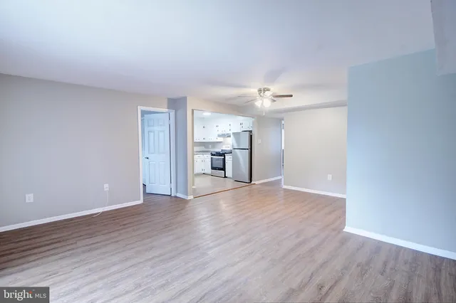 a view of a kitchen and an empty room with wooden floor